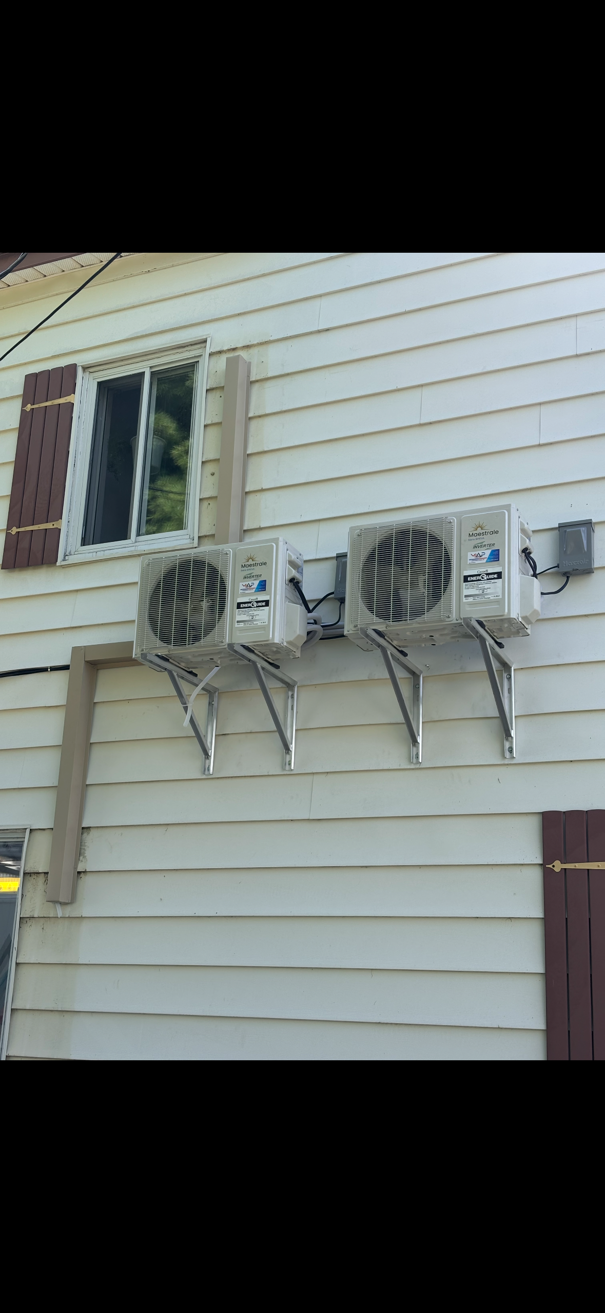 Trois climatiseurs sont montés sur le côté d'une maison.