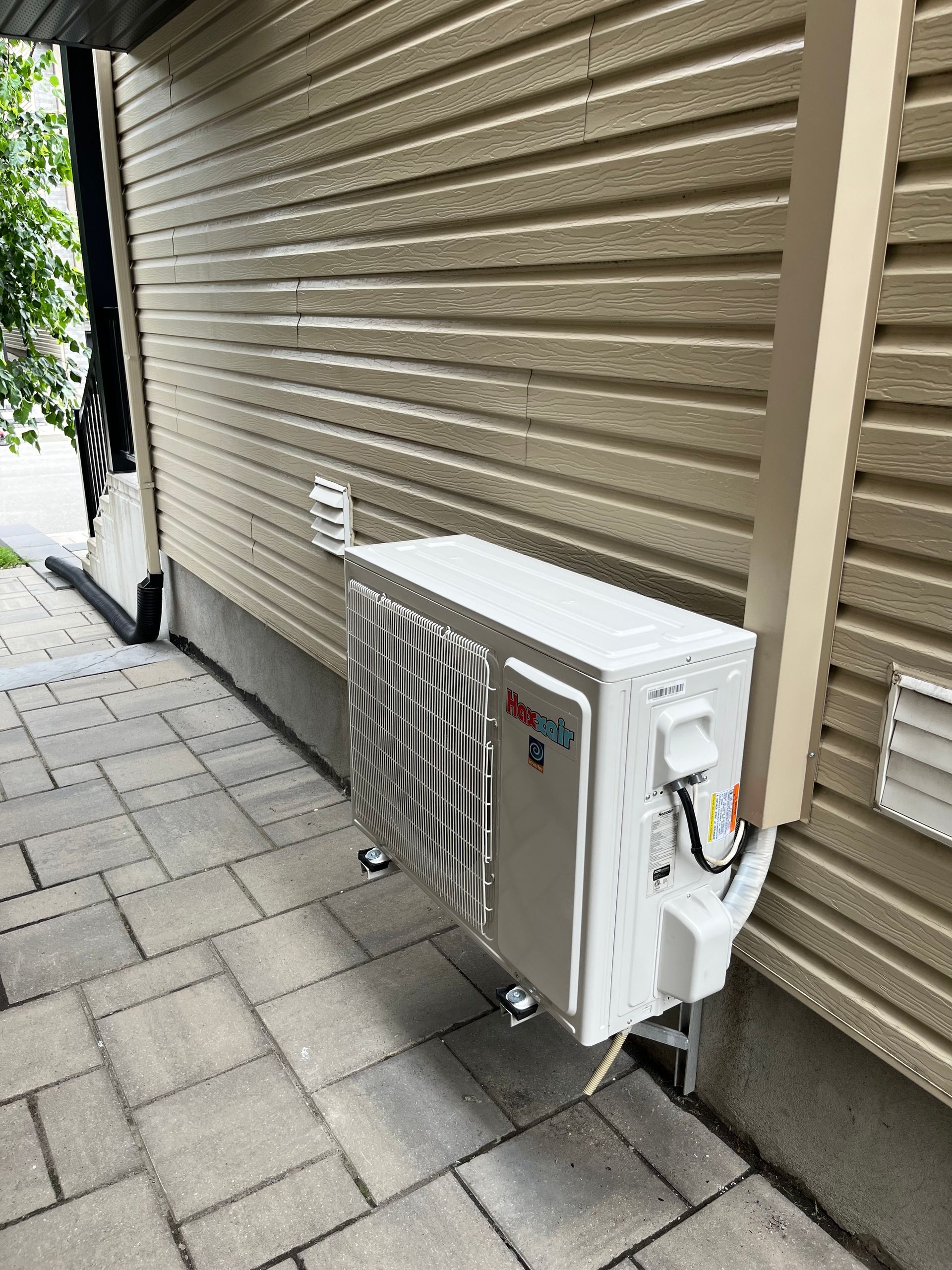 Un climatiseur blanc est posé sur le côté d'une maison.