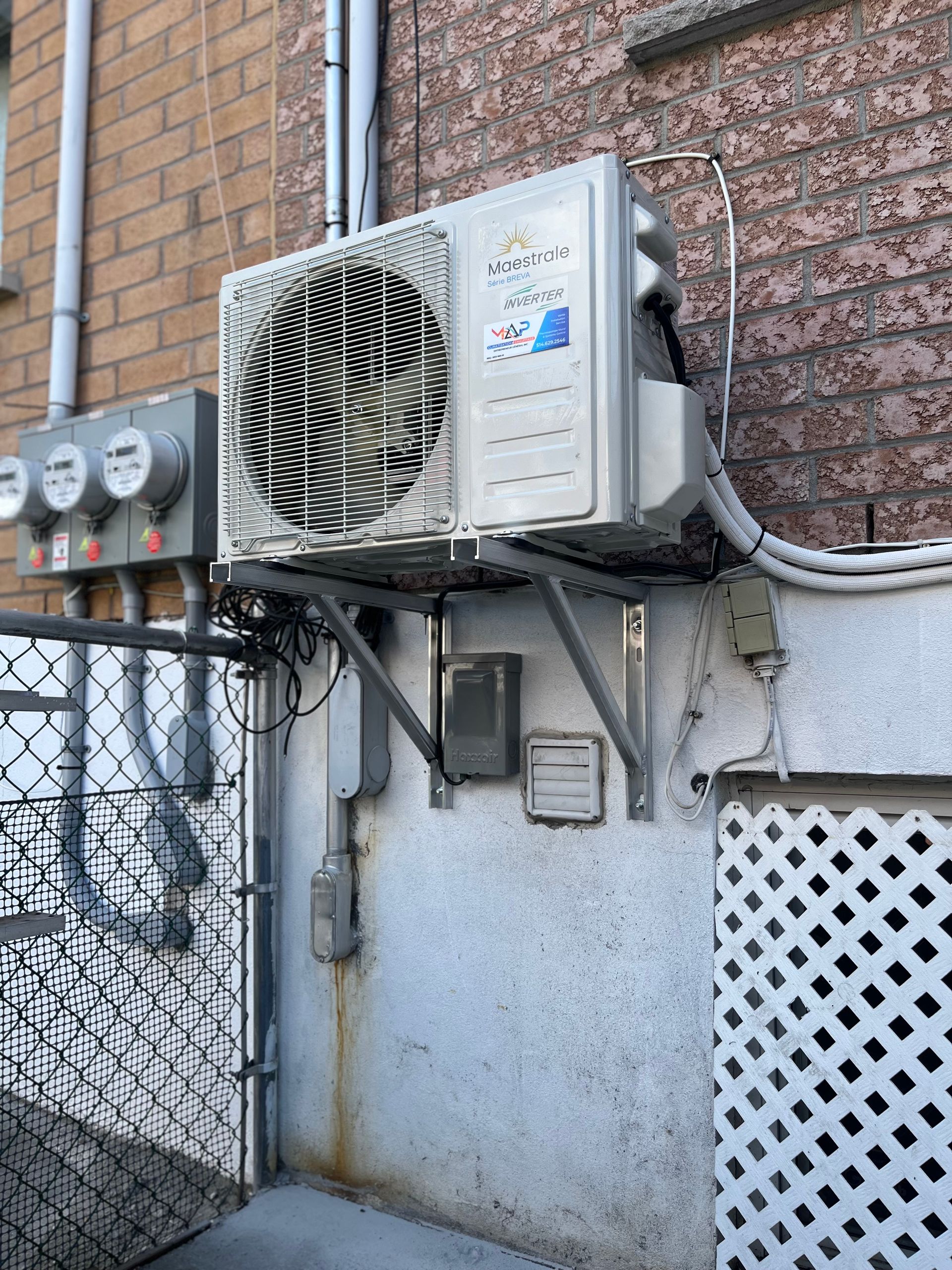 Un climatiseur est monté sur le côté d'un bâtiment en briques.