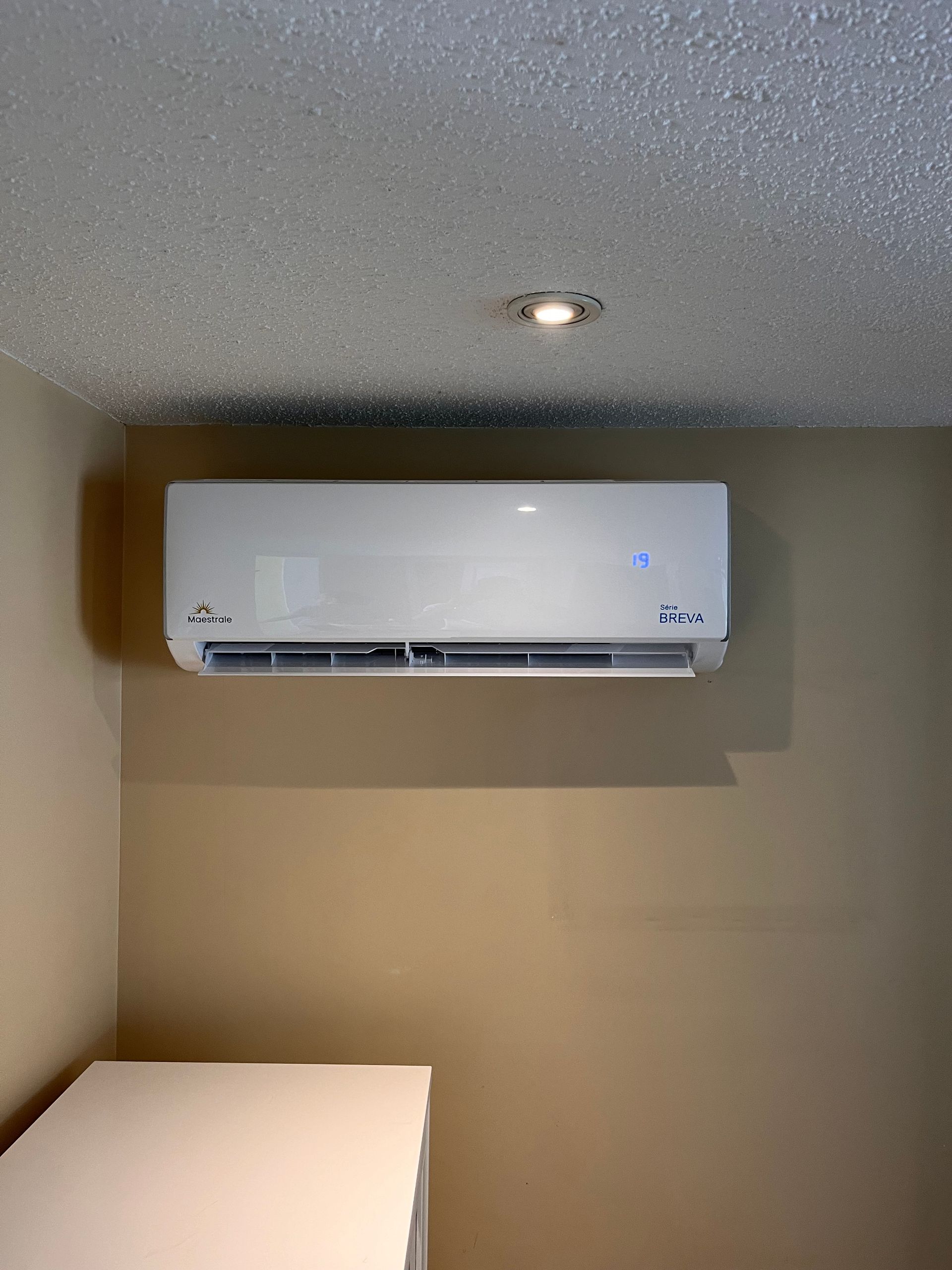 Un climatiseur blanc est suspendu au plafond d'une pièce.