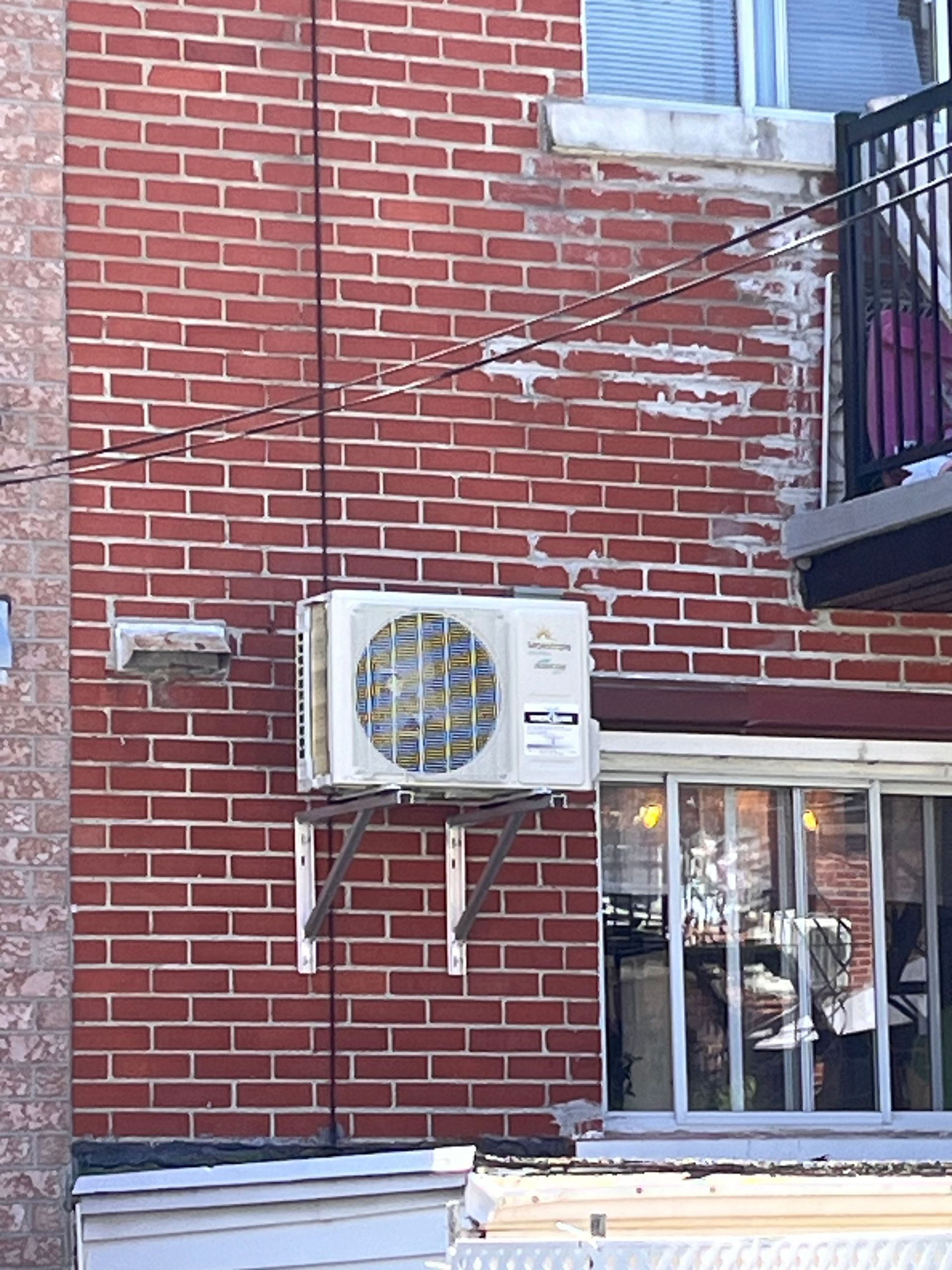 Un climatiseur blanc est monté sur le côté d'un bâtiment en briques.