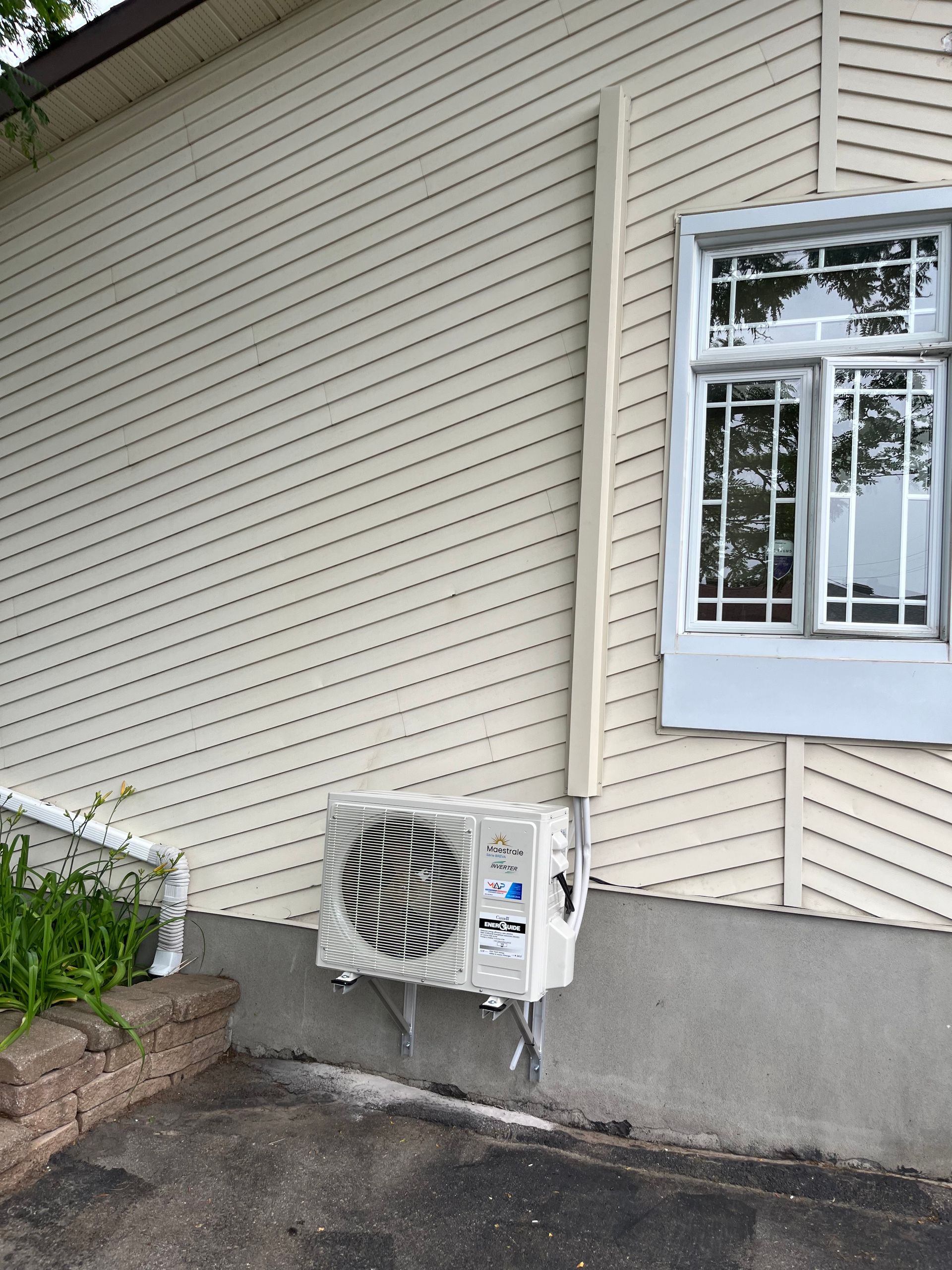Une maison blanche avec une fenêtre et un climatiseur sur le côté.