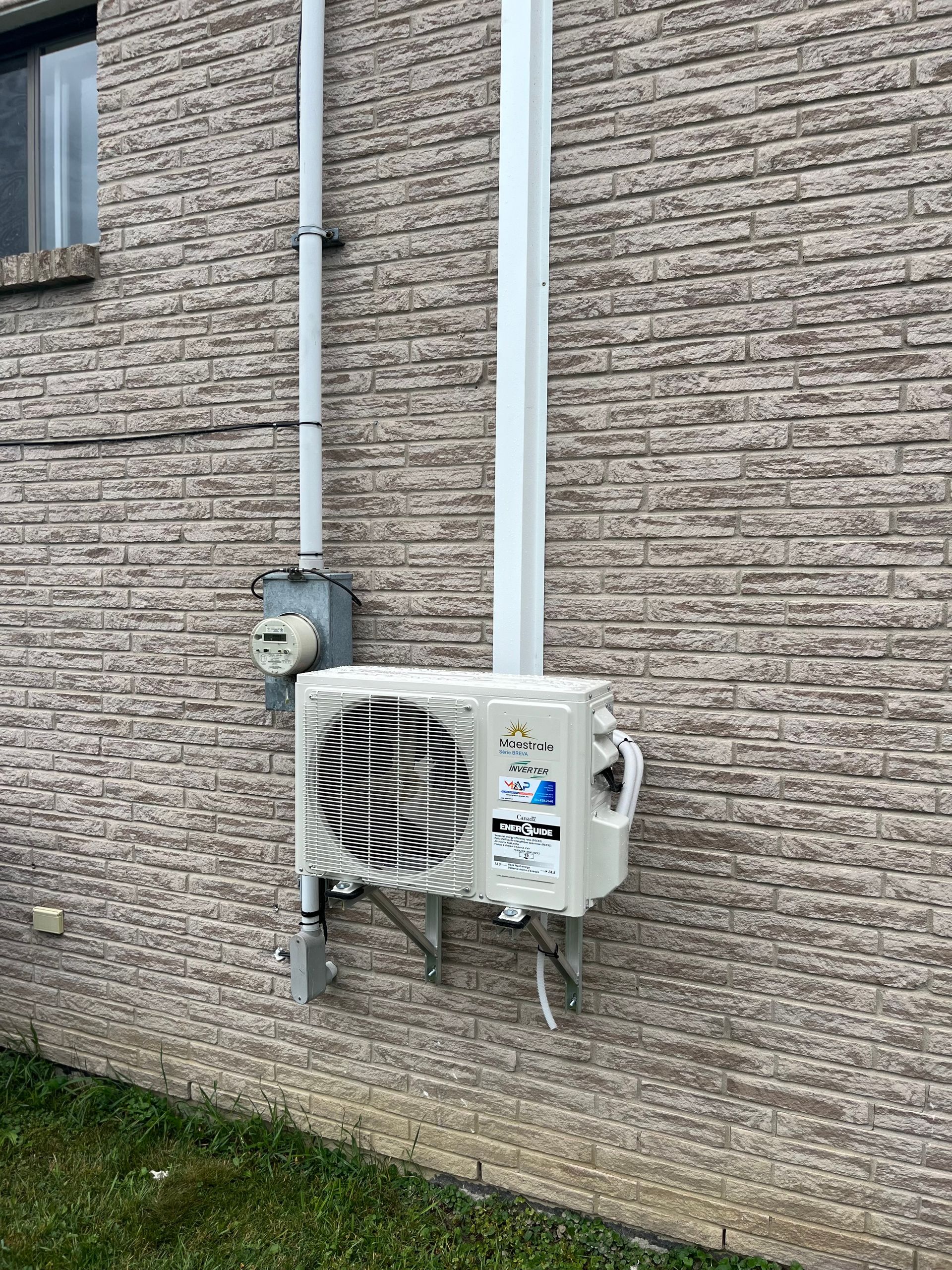 Un climatiseur blanc est monté sur le côté d'un bâtiment en briques.