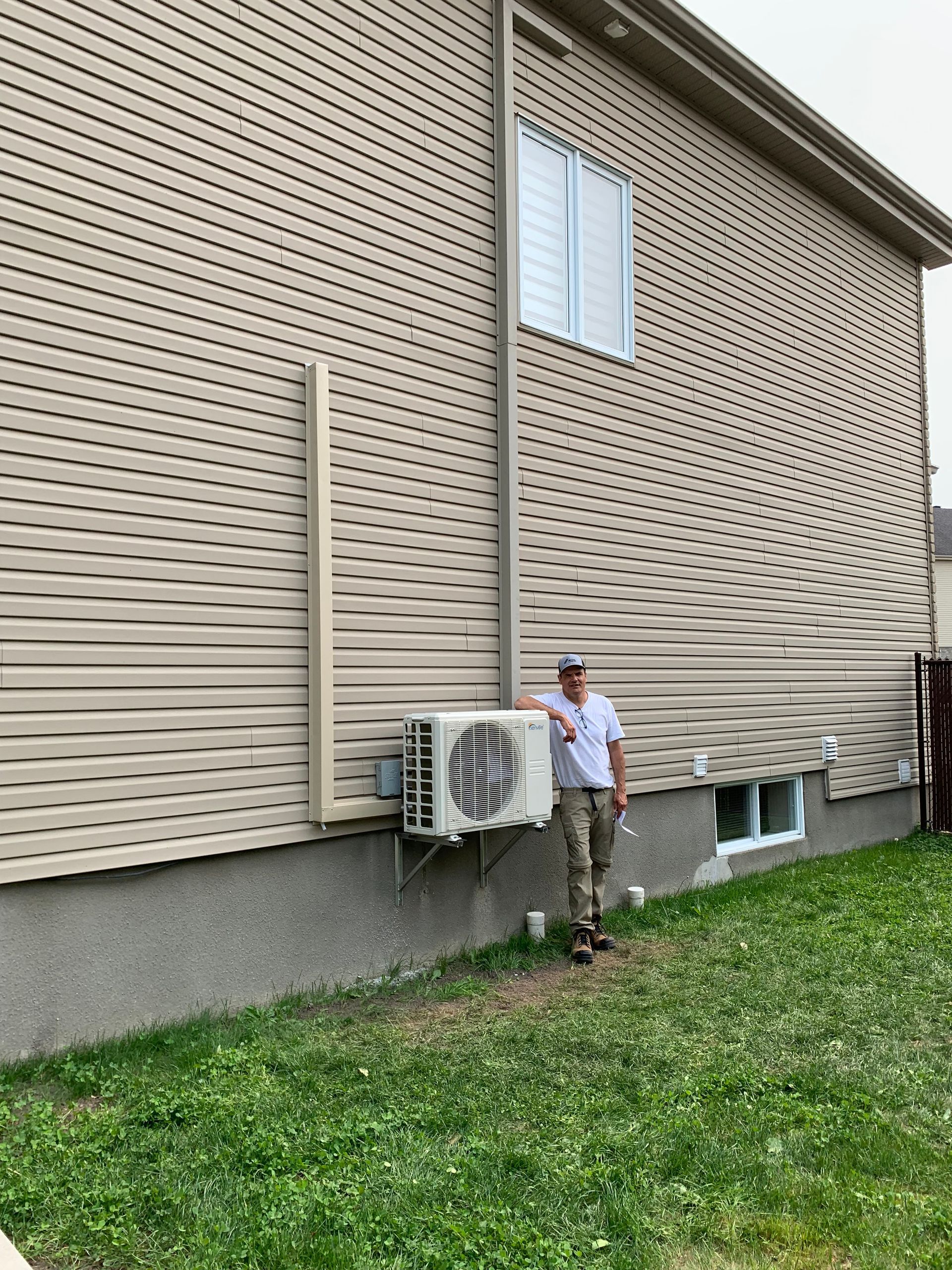 Un homme se tient devant une maison tenant un éventail.