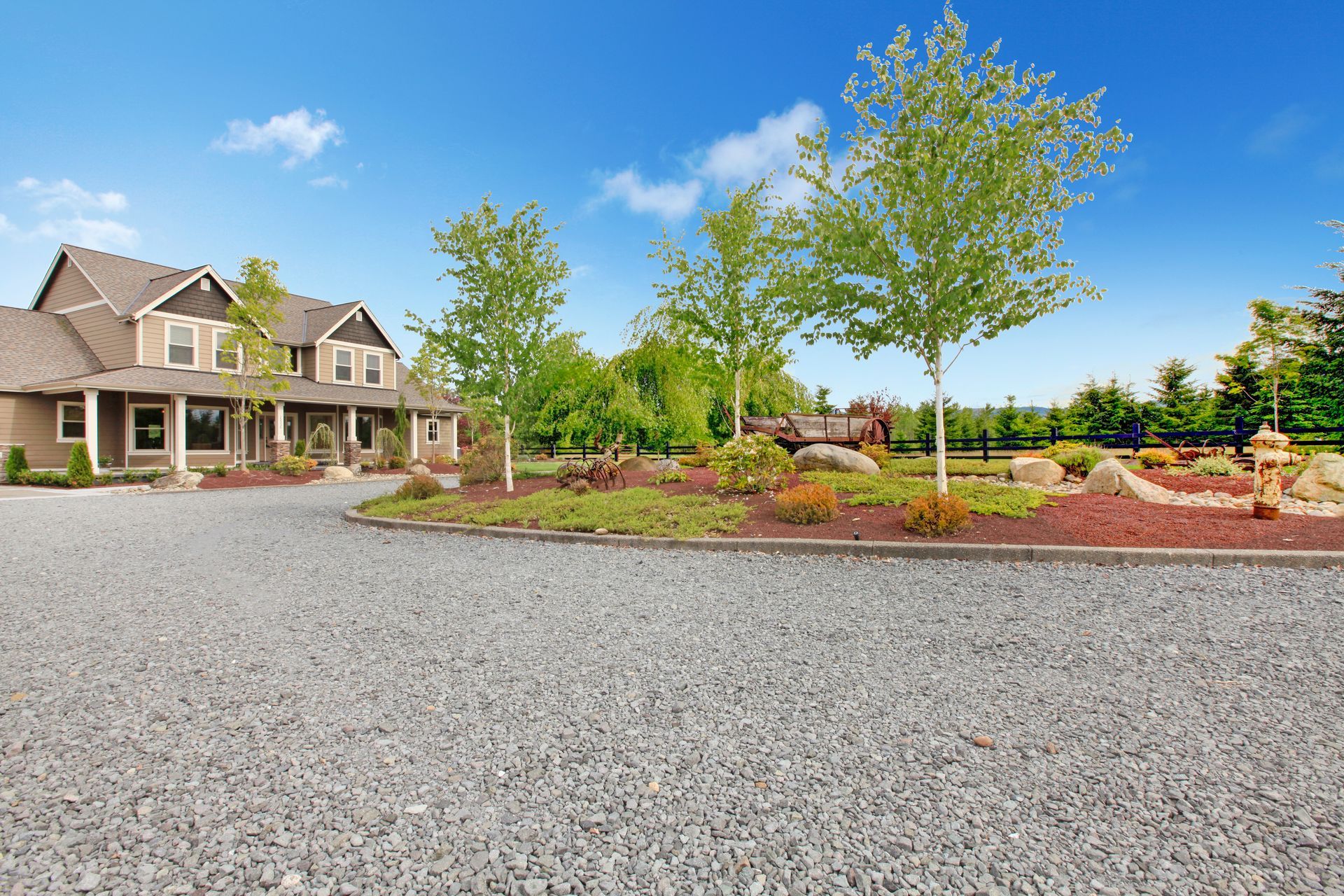 A gravel driveway leads to a landscaped home.]
