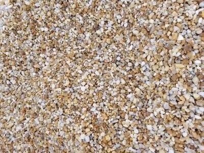 Close-up of small, light brown and white pebbles scattered together.