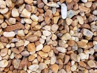 Close-up of a pile of small, smooth tan, brown, and white pebbles.