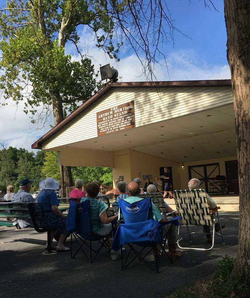 A group of people are sitting in front of a building with a sign on it