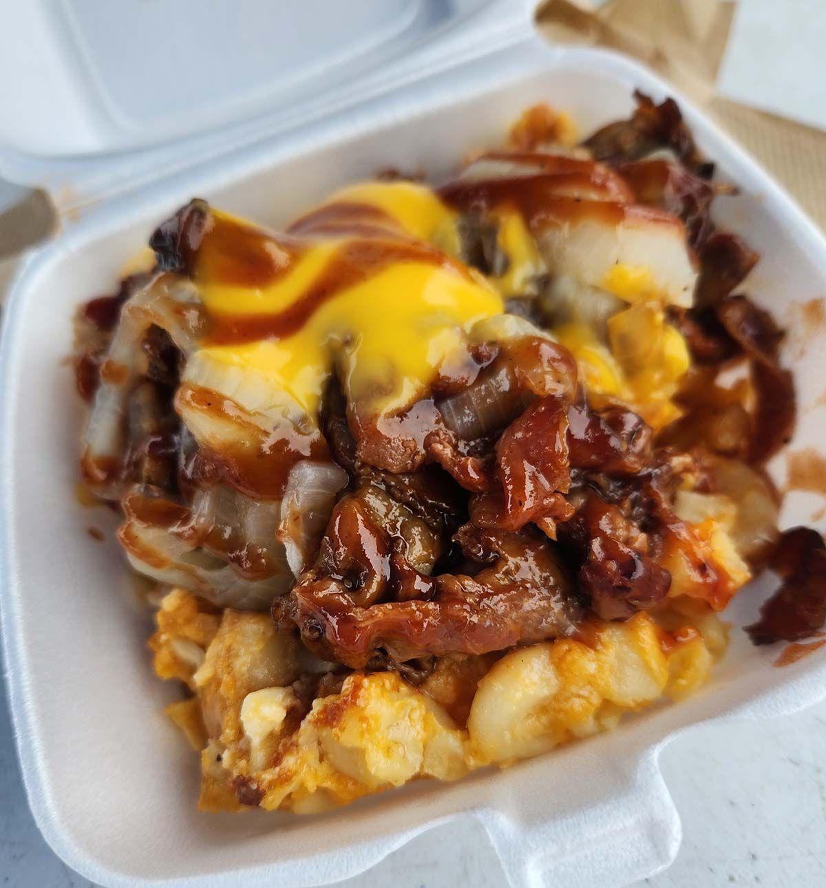 A styrofoam container filled with meat and cheese