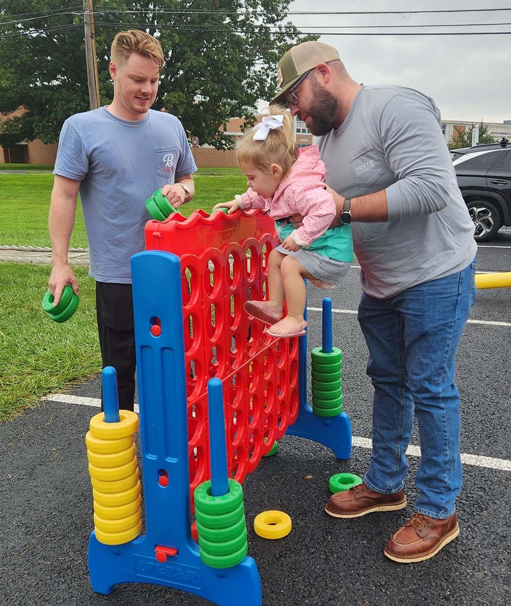 Two men and a little girl are playing a game of connect four