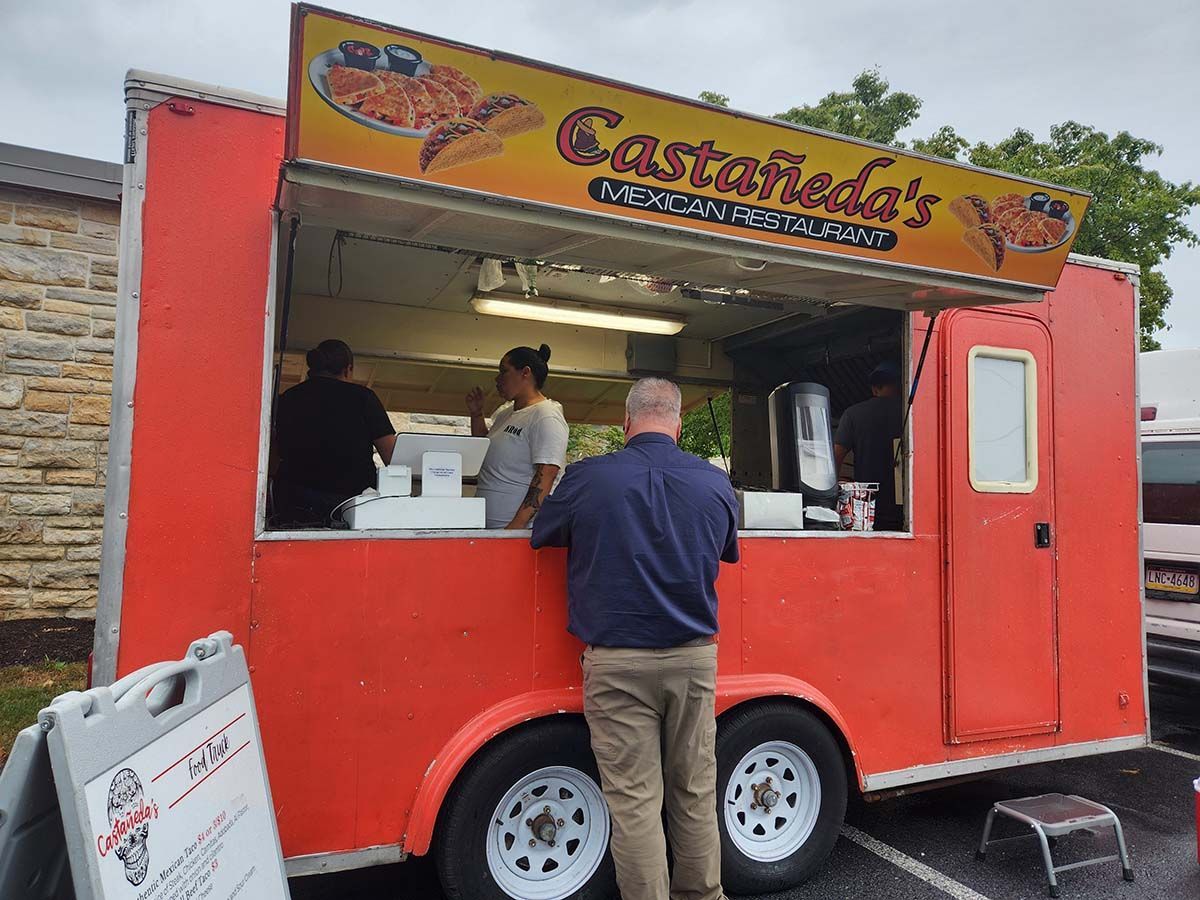 A man standing in front of a food truck that says castacuda 's