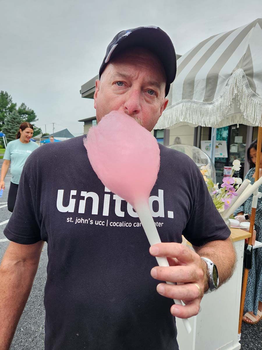 A man wearing a united shirt is eating cotton candy