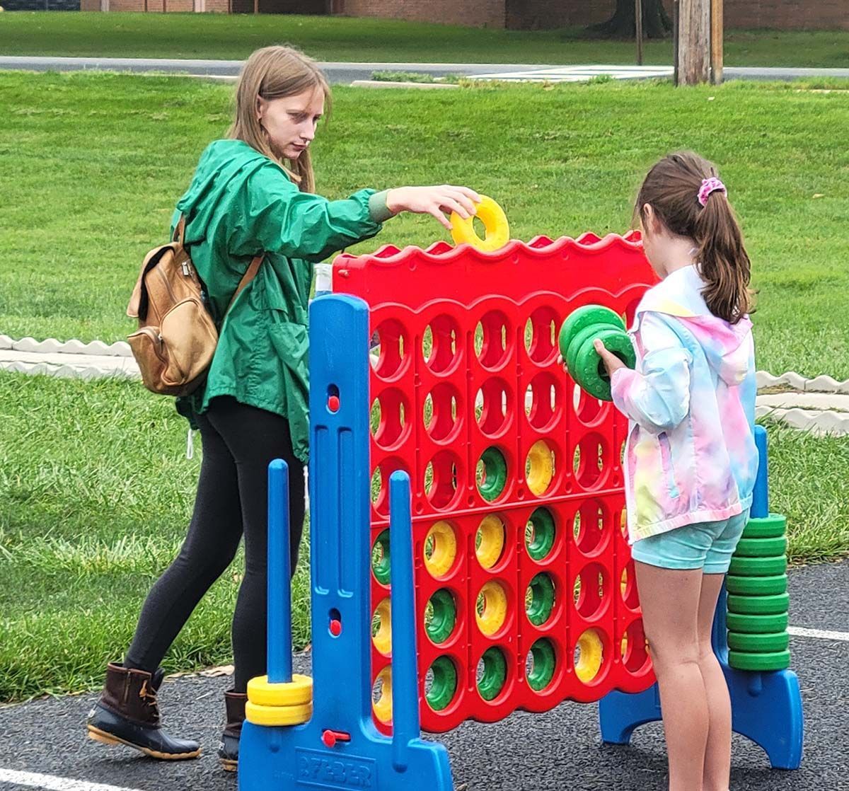 Two girls are playing a giant connect four game