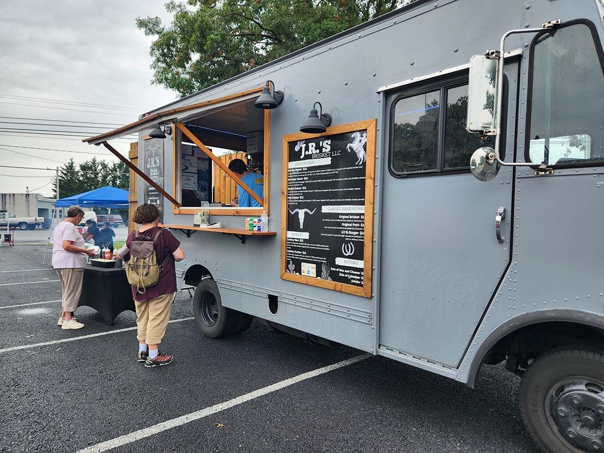 A gray food truck is parked in a parking lot