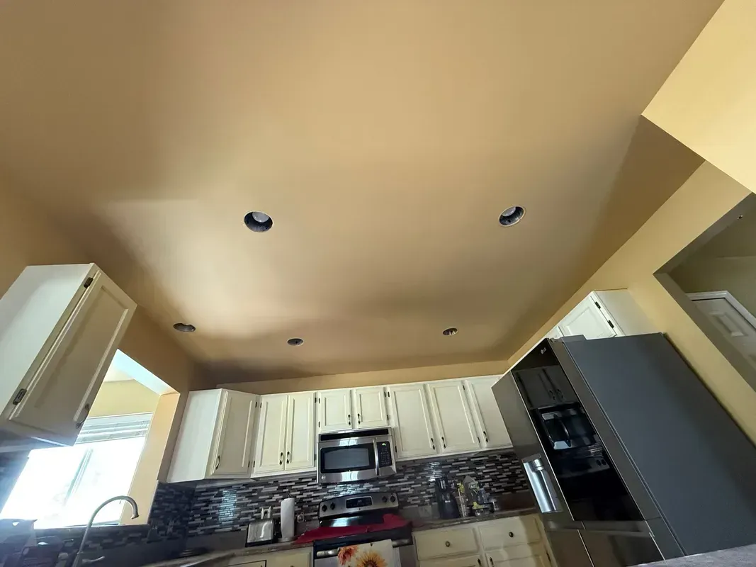 Kitchen with cream cabinets, dark backsplash, stove, and ceiling recessed lights.