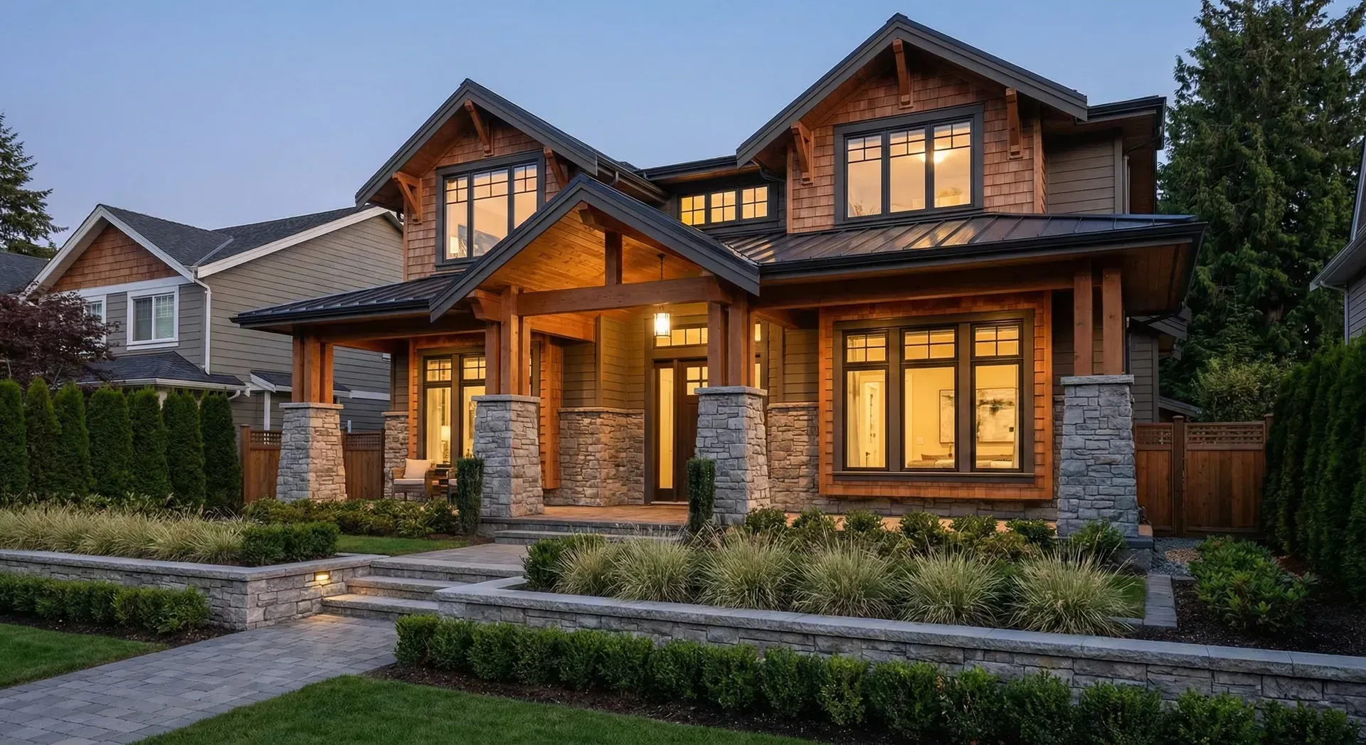 A large house with a gray roof is surrounded by trees and bushes.