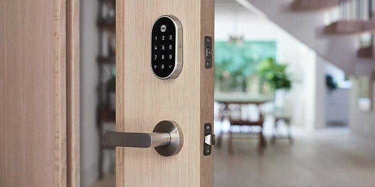 A door with a digital lock on it is open to a living room.