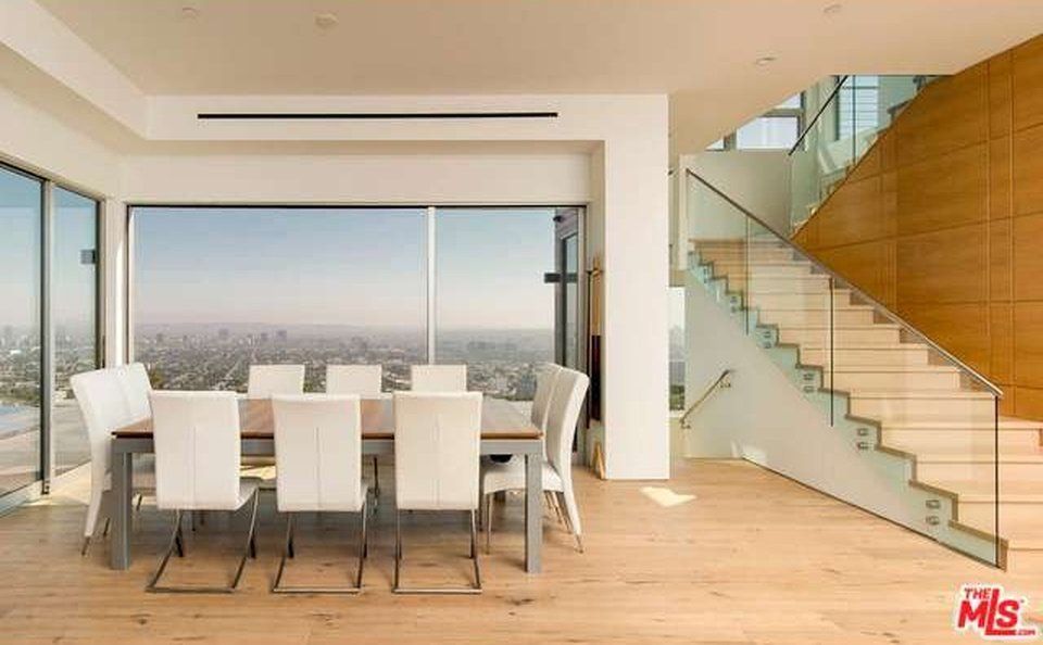 A dining room with a table and chairs and stairs with a view of the city.