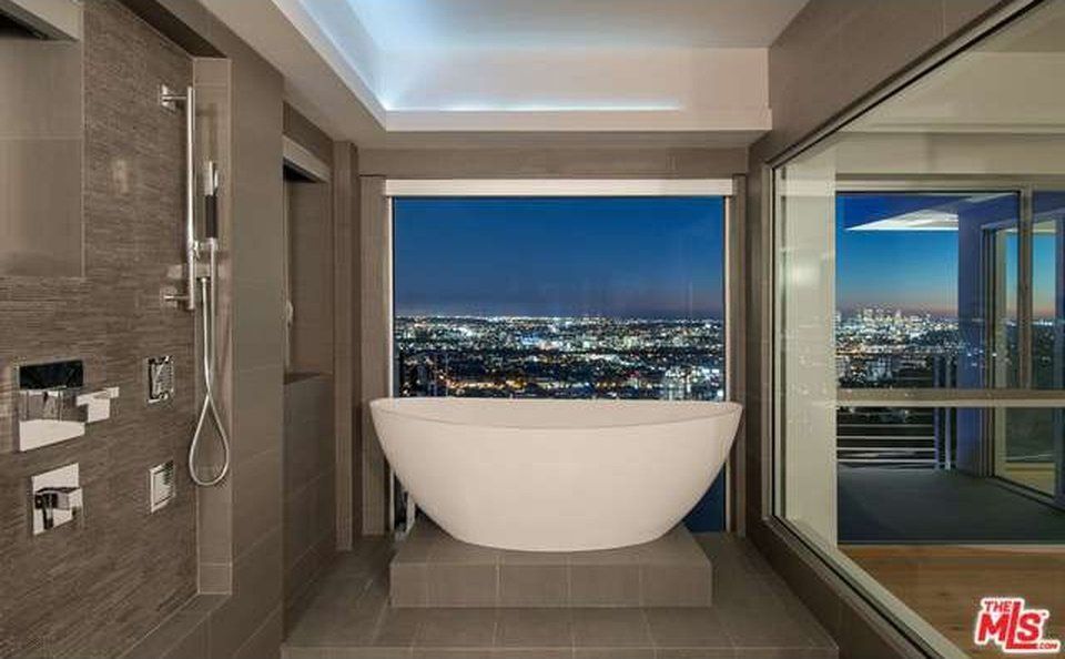 A bathroom with a bathtub and a view of the city