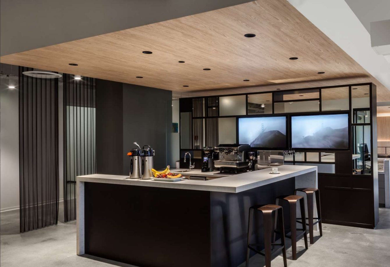 A kitchen with a large island and two televisions on the wall.