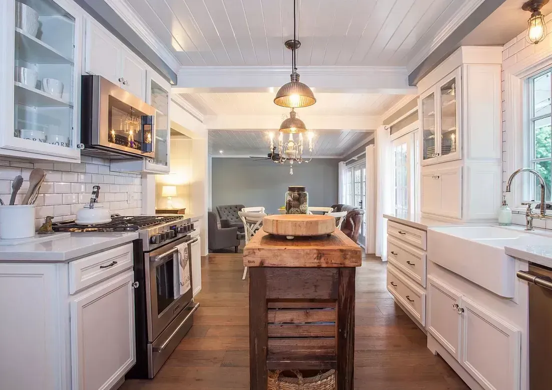 A kitchen with white cabinets , stainless steel appliances and a wooden island.