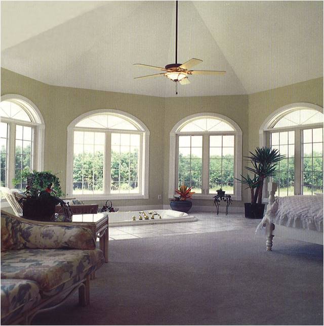 A bedroom with a ceiling fan and lots of windows