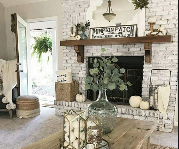 A living room with a fireplace and a coffee table decorated for fall.