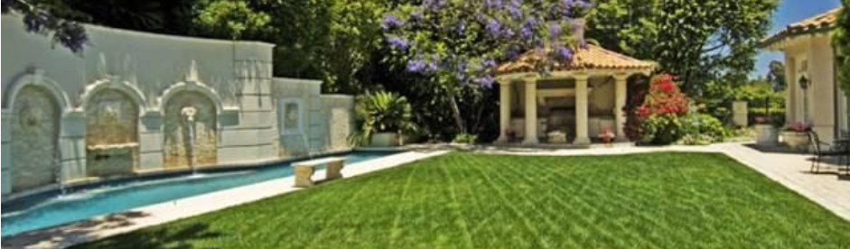 A large lawn with a swimming pool and a gazebo in the background.