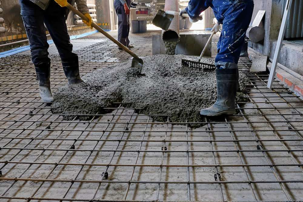 A Couple of Construction Workers Are Pouring Concrete Into a Grid — Nicks Readymix in Poona, QLD