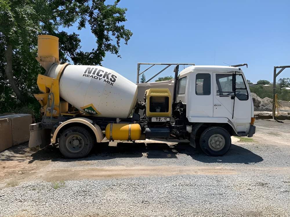 A White and Yellow Mixer Truck is Parked in a Gravel Lot — Nicks Readymix in Monkland, QLD
