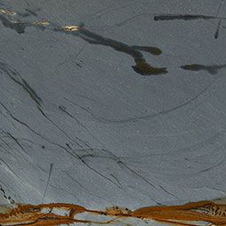 Abstract gray and brown textured surface with dark streaks and a small golden mark near the top