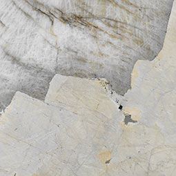White and gray stone surface with layered cracks and rough textured patches