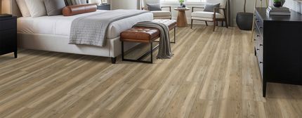 Modern bedroom with a bed, bench, and light wood flooring