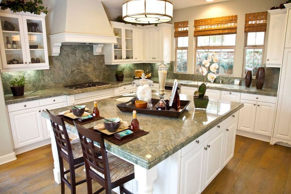 Bright kitchen with white cabinets, granite island, wood floor, and two bar stools.