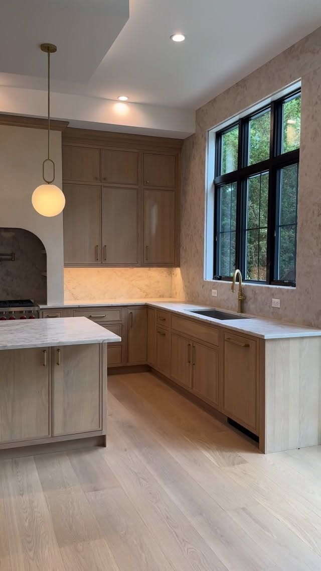 Bright kitchen with white cabinets, granite island, wood floor, and two bar stools.