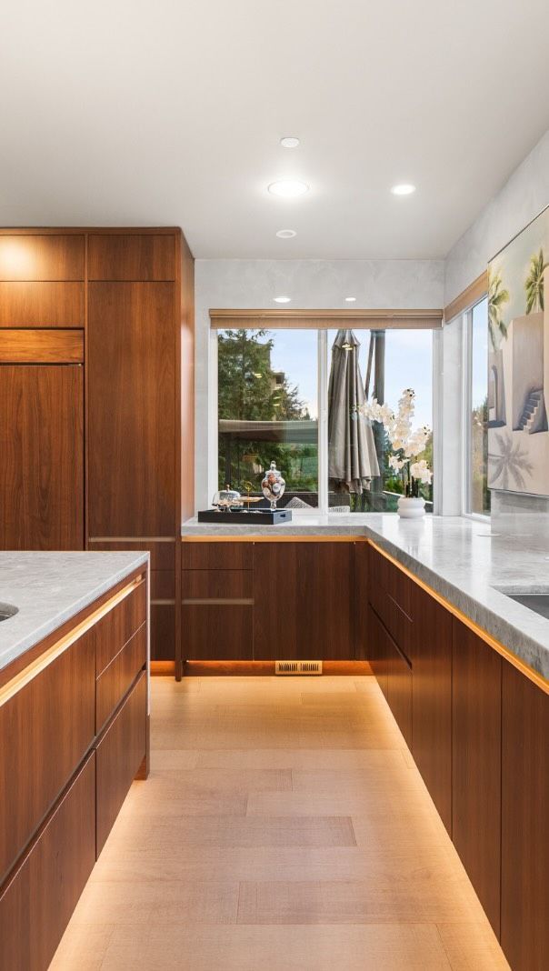 Modern white kitchen with gray cabinets, granite island, and stainless steel appliances