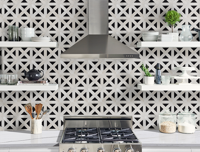 Modern kitchen backsplash with white geometric tile, stainless range hood, shelves, and countertop decor