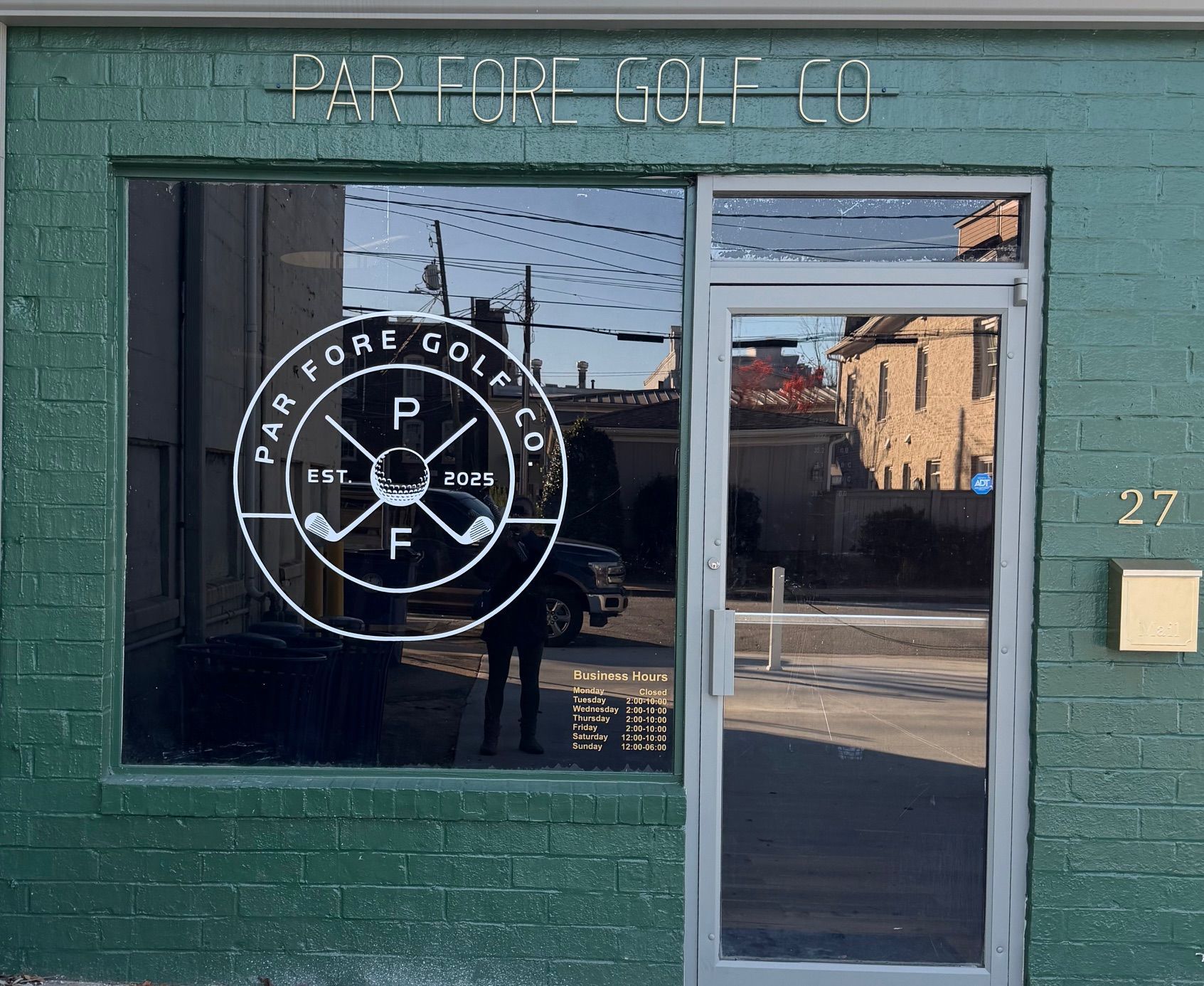 Golf balls in a green basket, top-down view. White balls with black lines sit on green grass.