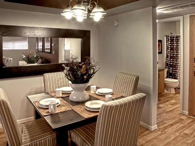 A dining room with a table and chairs and a mirror