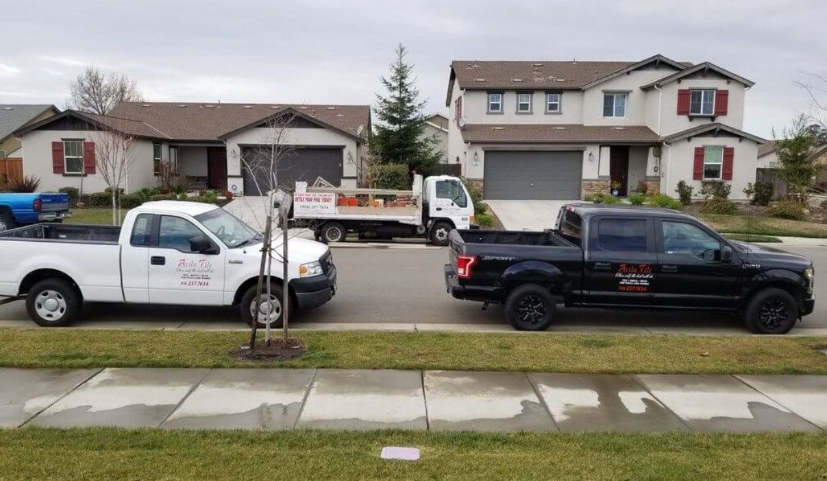 Two pickup trucks are parked in front of a house.