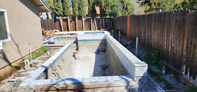 A swimming pool is being built in the backyard of a house.