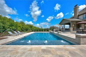 There is a large swimming pool in the backyard of a house.