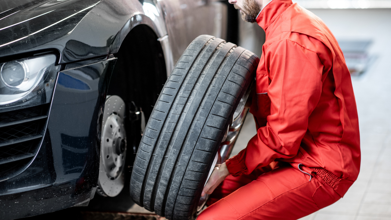 A mechanic is changing a tire on a car in a garage.