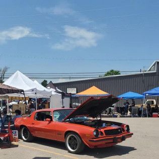 A red car with the hood up is parked in a parking lot.