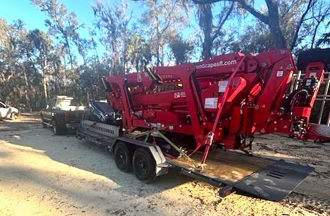 Red tree chipper on a trailer, ready for transport, outdoors.