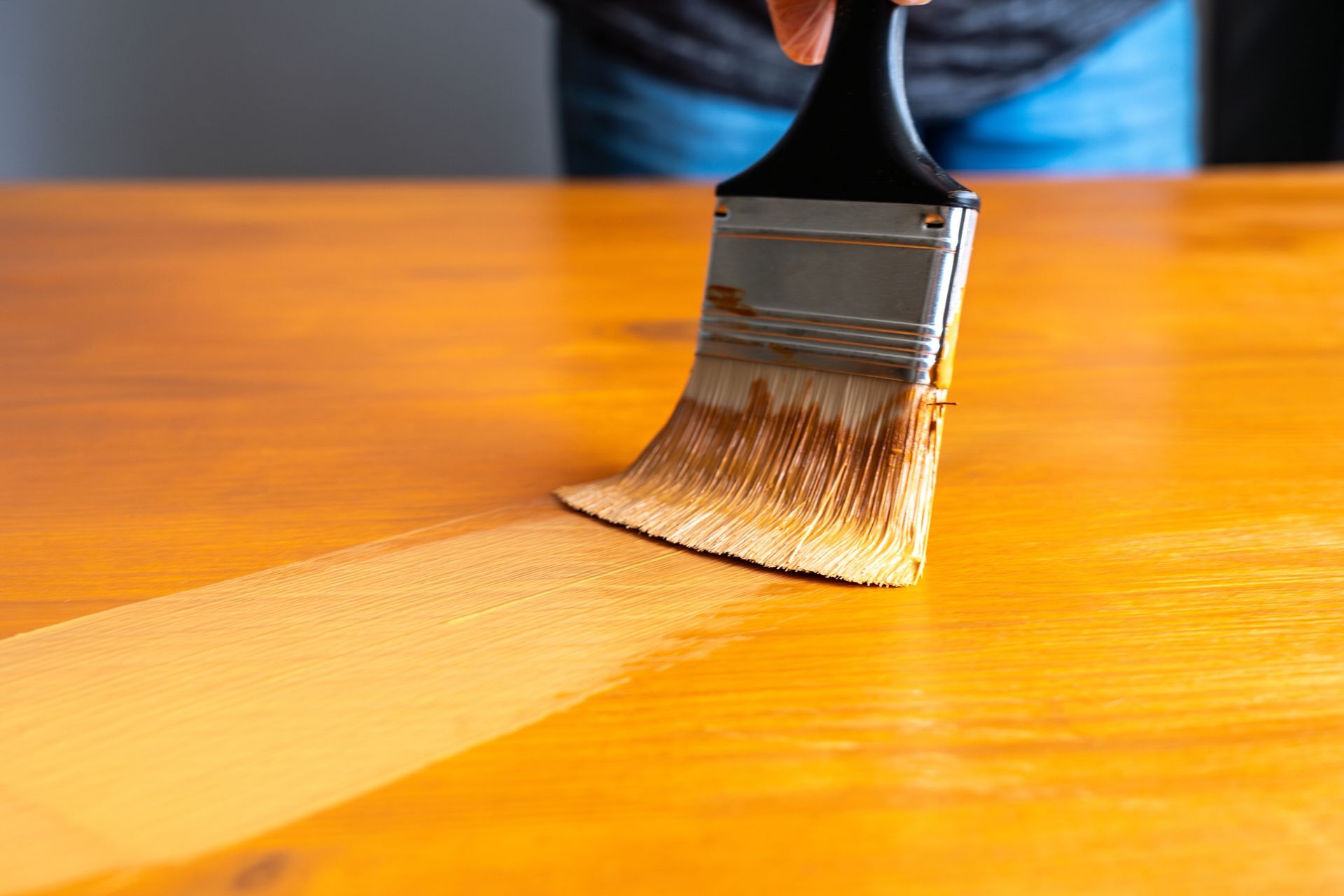 A person is painting a wooden table with a brush.