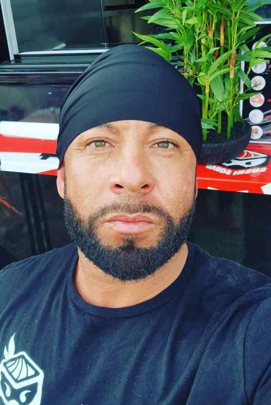 A sushi chef with a beard wearing a black headband