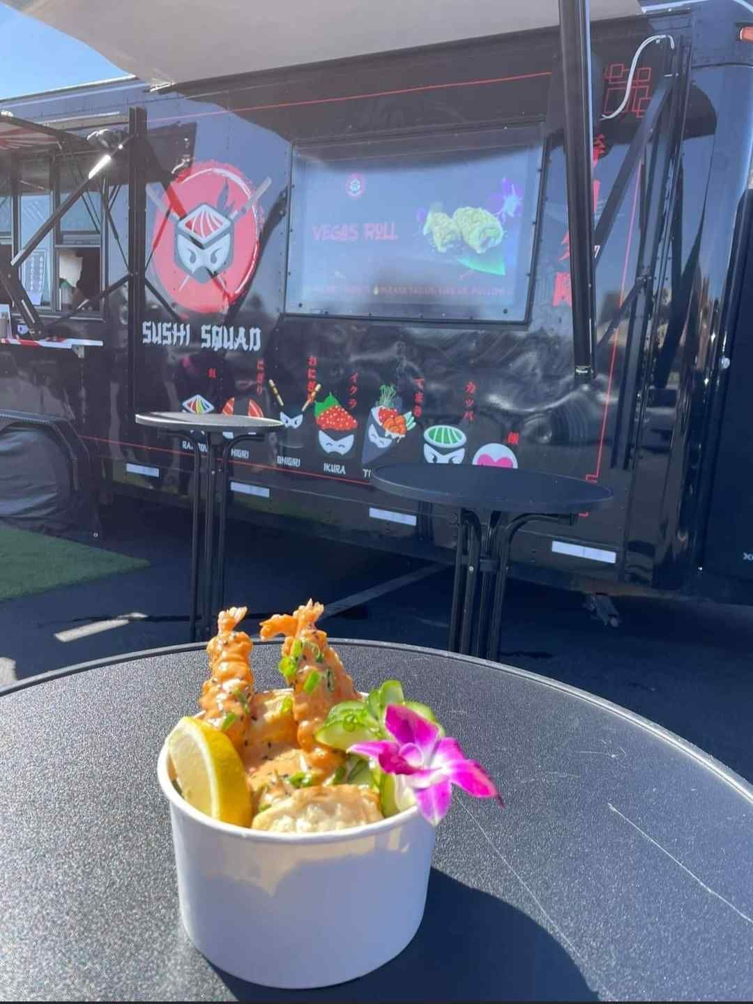 A bowl of food is sitting on a table in front of a food truck.