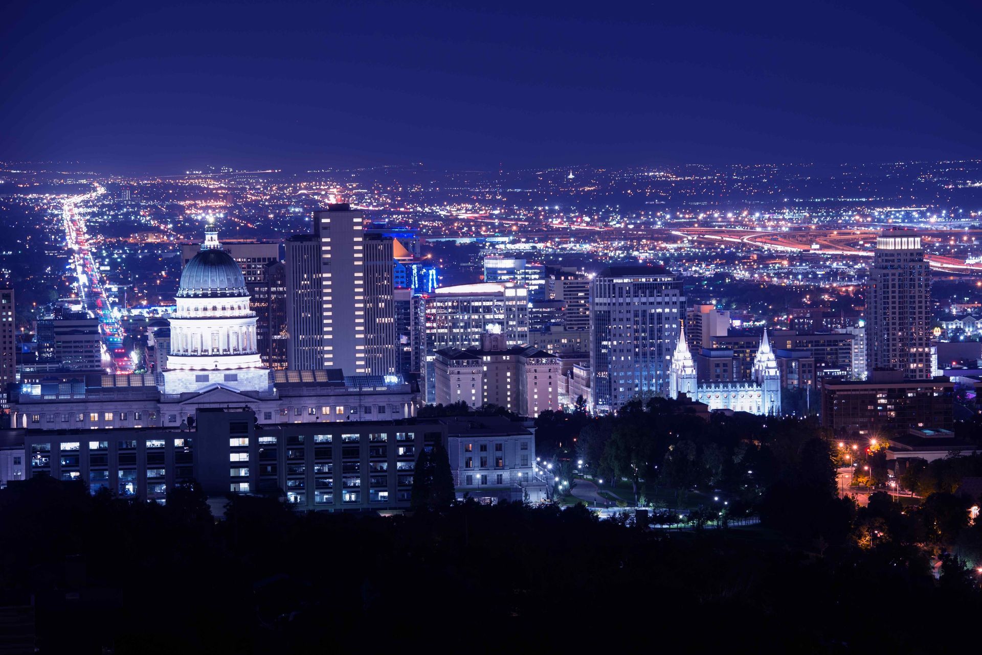An aerial view of a city at night with a dome shaped building in the foreground.