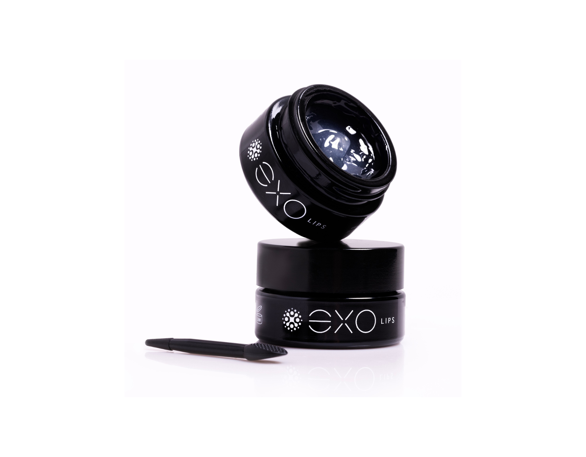 Two small black jars of gel with a tool, lit against a white background. One jar tilted atop the other.